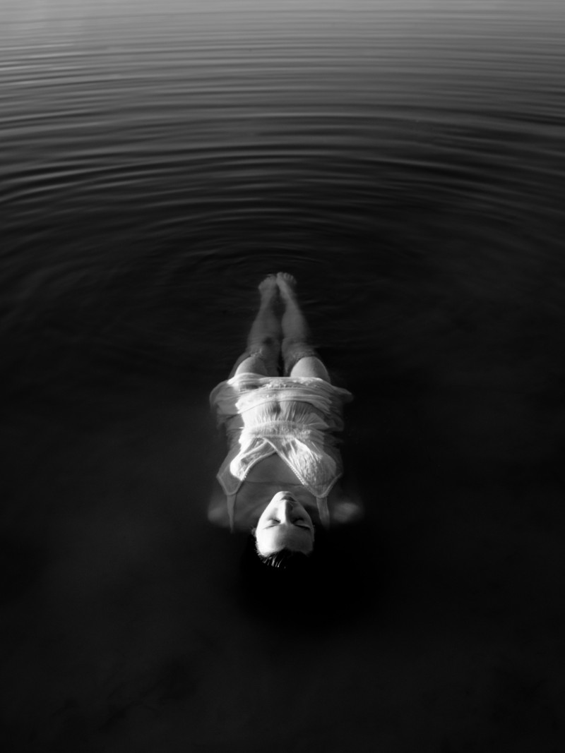 woman wearing white spaghetti-strap top near body of water